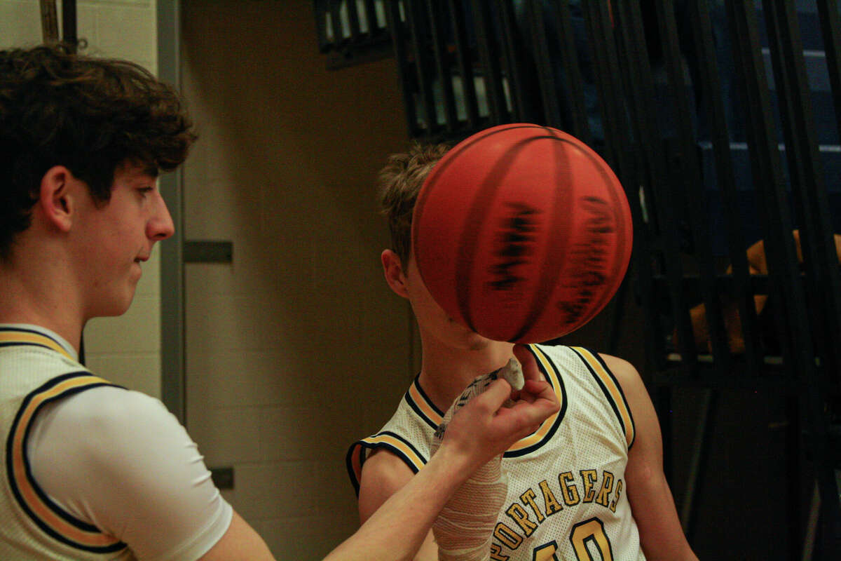Onekama freshman Tyler Hart (left) attempts to place the ball on the hand of Sawyer Christensen while keeping the ball in motion before a game against Grand Traverse Academy on Feb. 28, 2023 at Onekama Consolidated Schools. 