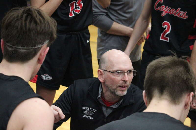 Reed City boys basketball coach Brennan Walsh talks to his team during a timeout in a recent game.