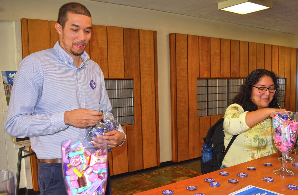 Miranda Araujo (right) of Seneca chooses some candy while Cameron Sweatman, assistant director for diversity, inclusion and belonging, finishes setting up a display at Illinois College for Women's History Month.