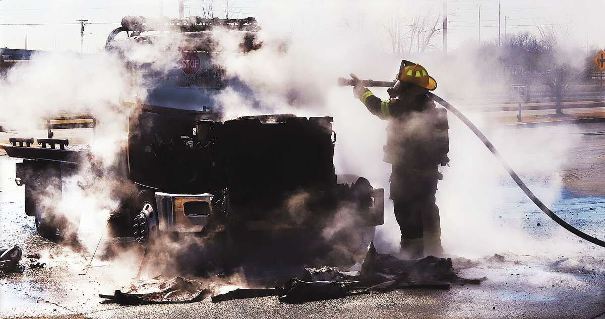 An Alton firefighter moves through the smoke to finish extinguishing the burning flatbed tow truck on Tuesday afternoon.
