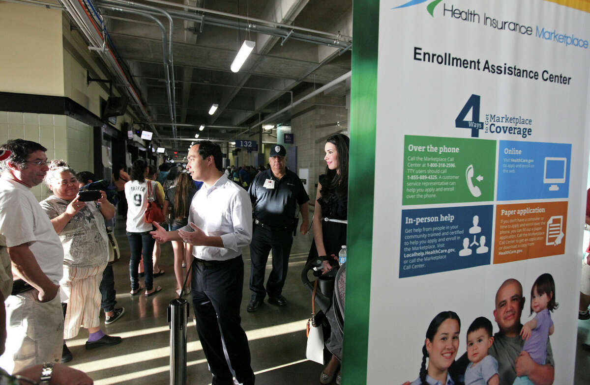 U.S. Rep. Joaquin Castro (center) talks with people lined up to enroll for health insurance under the Affordable Care Act at the Alamodome Monday, March 31, 2014 as his wife Anna (center right) looks on.