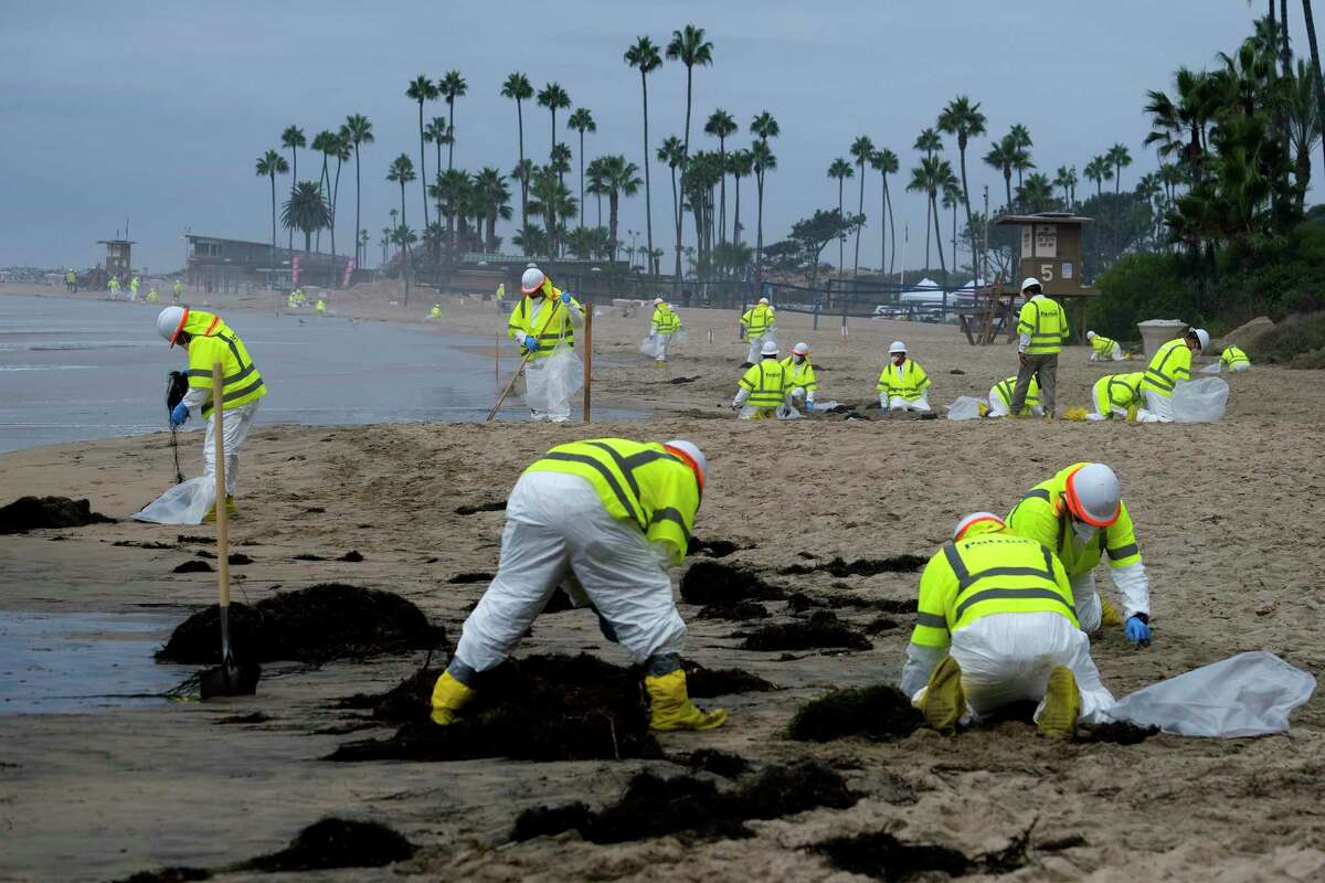 Workers in protective suits clean the contaminated beach in Corona Del Mar after an oil spill in Newport Beach, Calif., Oct. 7, 2021. Shipping companies have agreed to pay nearly $97 million to settle a lawsuit with a pipeline operator over a 2021 oil spill off the coast of Southern California. Amplify Energy, the Houston-based company that operates the pipeline, said Wednesday, March 1, 2023, that companies associated with the M/V Danit and M/V Beijing had agreed to the payments.