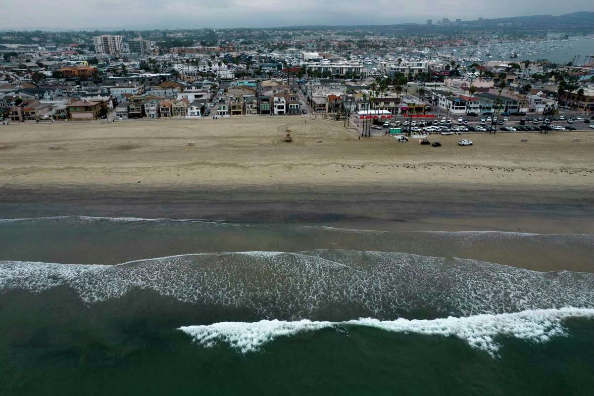 This aerial image taken with a drone, shows the closed beach after oil washed up in Newport Beach, Calif., on Oct. 7, 2021. Shipping companies have agreed to pay nearly $97 million to settle a lawsuit with a pipeline operator over a 2021 oil spill off the coast of Southern California. Amplify Energy, the Houston-based company that operates the pipeline, said Wednesday, March 1, 2023, that companies associated with the M/V Danit and M/V Beijing had agreed to the payments.