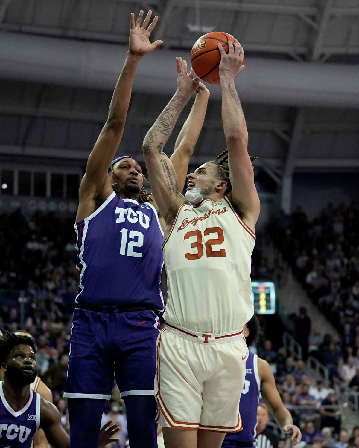 TCU forward Xavier Cork (12) defends against a shot by Texas's Christian Bishop (32) in the first half of an NCAA college basketball game, Wednesday, March 1, 2023, in Fort Worth Texas. (AP Photo/Tony Gutierrez)