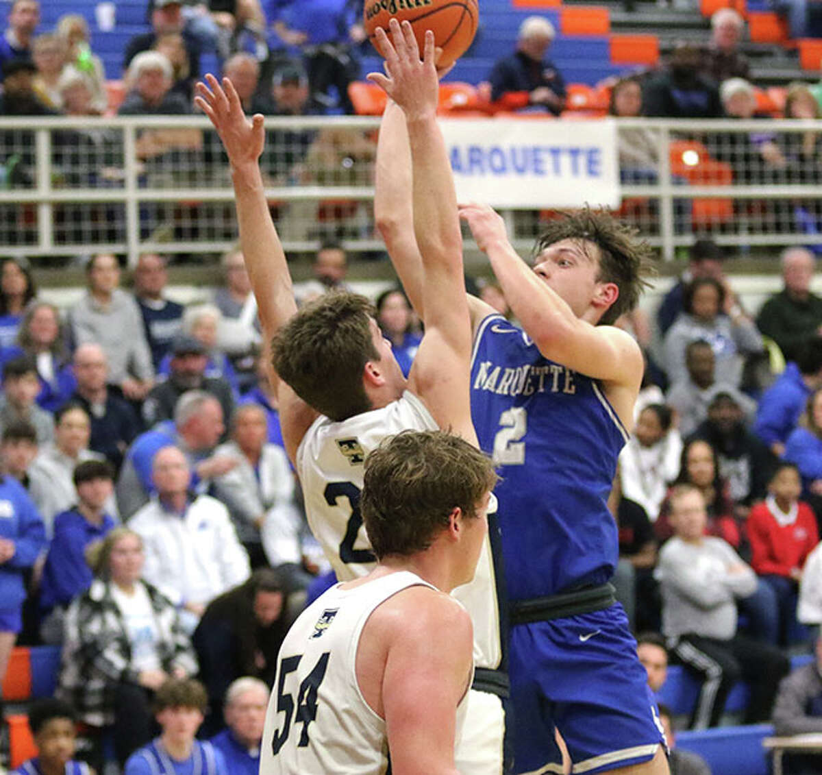 Marquette Catholic's Braden Kline (right) puts up a shot in the lane over T-Town's James Niebrugge in the second half in a Class 2A sectional semifinal on Wednesday night in Newton.