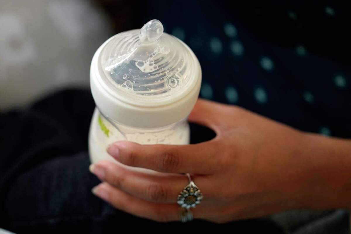 FILE - A mother holds a bottle of baby formula as she feeds her infant son, Friday, May 13, 2022, in San Antonio. Federal health officials are warning parents of newborns, Thursday, March 2, 2023, to sterilize equipment used for both bottle- and breast-feeding after a baby died last year from a rare infection tied to a contaminated breast pump.