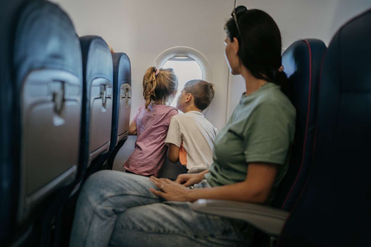 A stock image of a mother with two children traveling on a commercial flight.