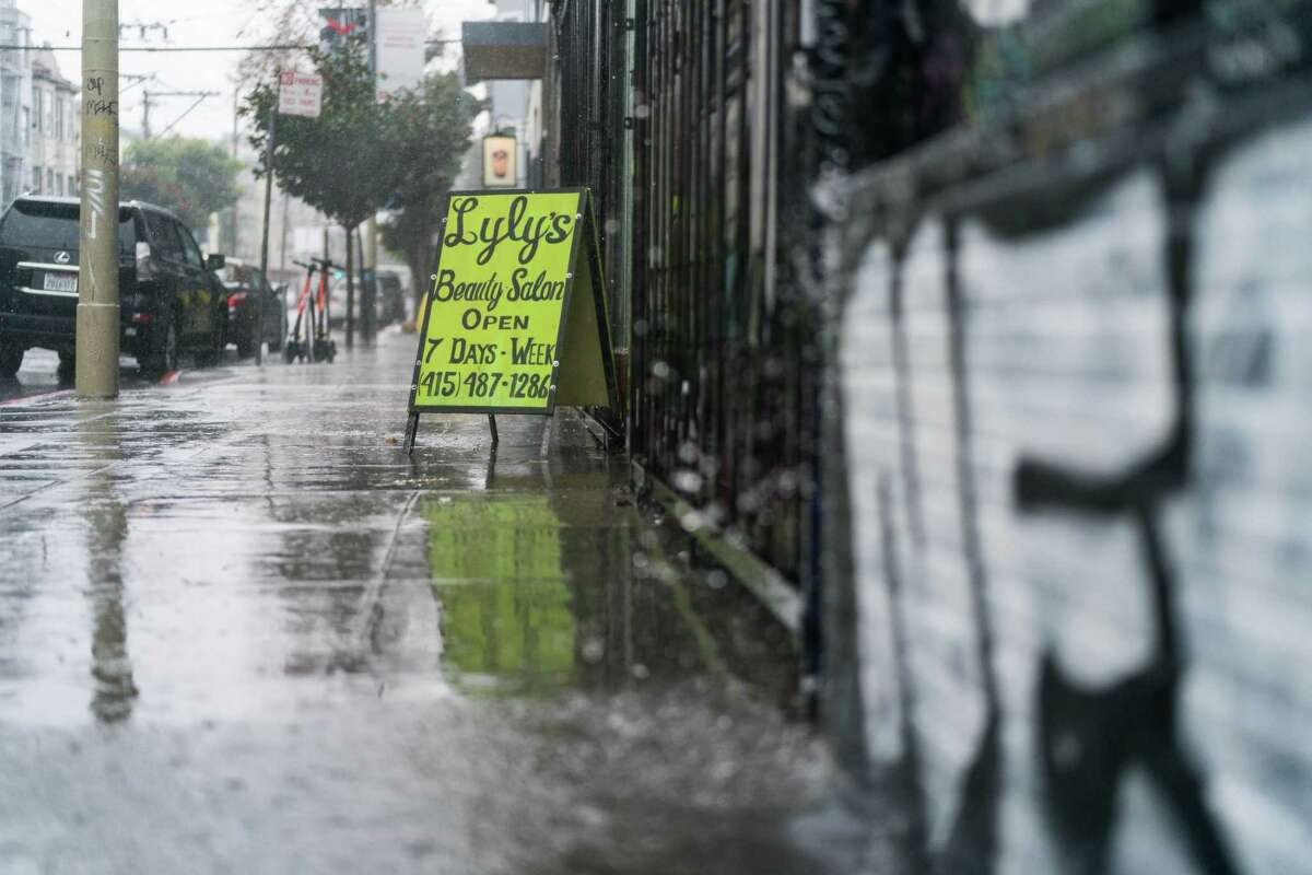 A sign for a beauty salon is seen as water pours off the building during heavy rain in San Francisco in December.