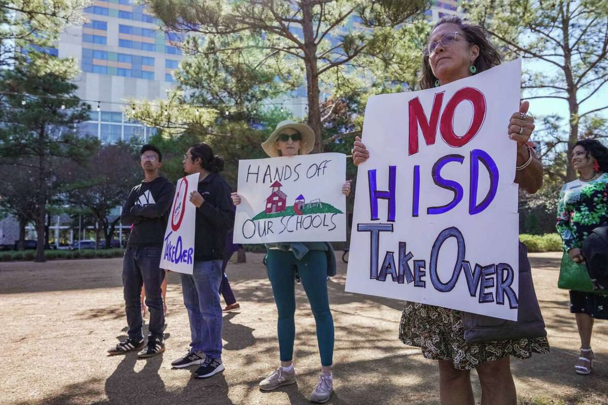 Teachers Patricia Allen, 65 and Marcela Cook, 58 hold us signs at a March 3 press conference led by Mayor Sylvester Turner and other community leaders who want to save the Houston Independent School District from a state takeover and protect public education.