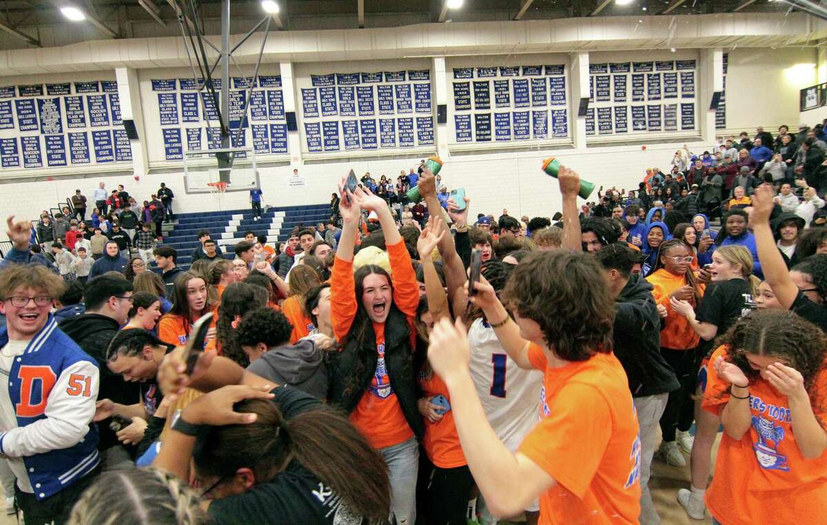 Danbury students spill onto the court after the team defeated Staples in FCIAC Boys' Basketball Championship game action in Wilton, Conn., on Friday March 3, 2023.