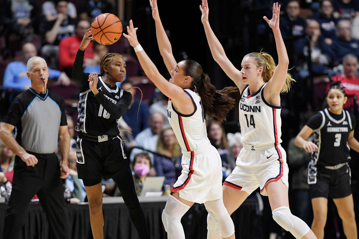 Georgetown's Kennedy Fauntleroy (10) passes under pressure from UConn's Nika Muhl and Dorka Juhasz (14) during the first half of an NCAA college basketball game in the quarterfinals of the Big East Conference tournament at Mohegan Sun Arena, Saturday, March 4, 2023, in Uncasville, Conn. (AP Photo/Jessica Hill)