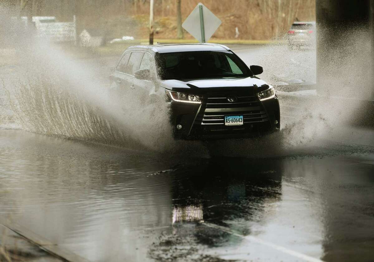 A car crosses a flooded viaduct during storm flooding on Old Gate Lane in Milford, Conn. on Saturday, March 04, 2023.