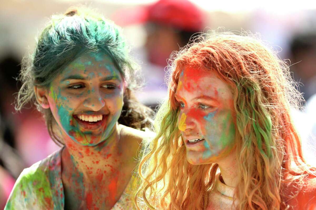 Holi attendees Riddle Jain, left, laughs alongside Lauren as they walk through the festival covered in colored powder during a celebration at Hindu Temple Of The Woodlands, Saturday, March 4, 2023, in The Woodlands. The festival celebrates the love of gods Radha and Krishna and the triumph of good over evil. Held every March, it also commemorates the beginning of spring, good harvests and a return of color to the world.