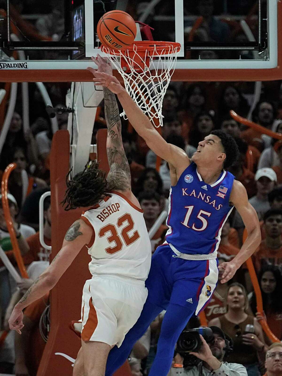 Texas forward Christian Bishop (32) is blocked by Kansas guard Kevin McCullar Jr. (15) during the first half of an NCAA college basketball game in Austin, Texas, Saturday, March 4, 2023. (AP Photo/Eric Gay)