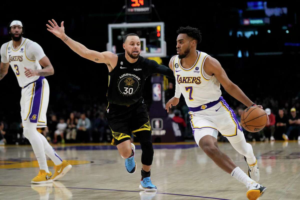 Los Angeles’ Troy Brown Jr. drives past Warriors guard Stephen Curry on Sunday. The host Lakers won 113-105.