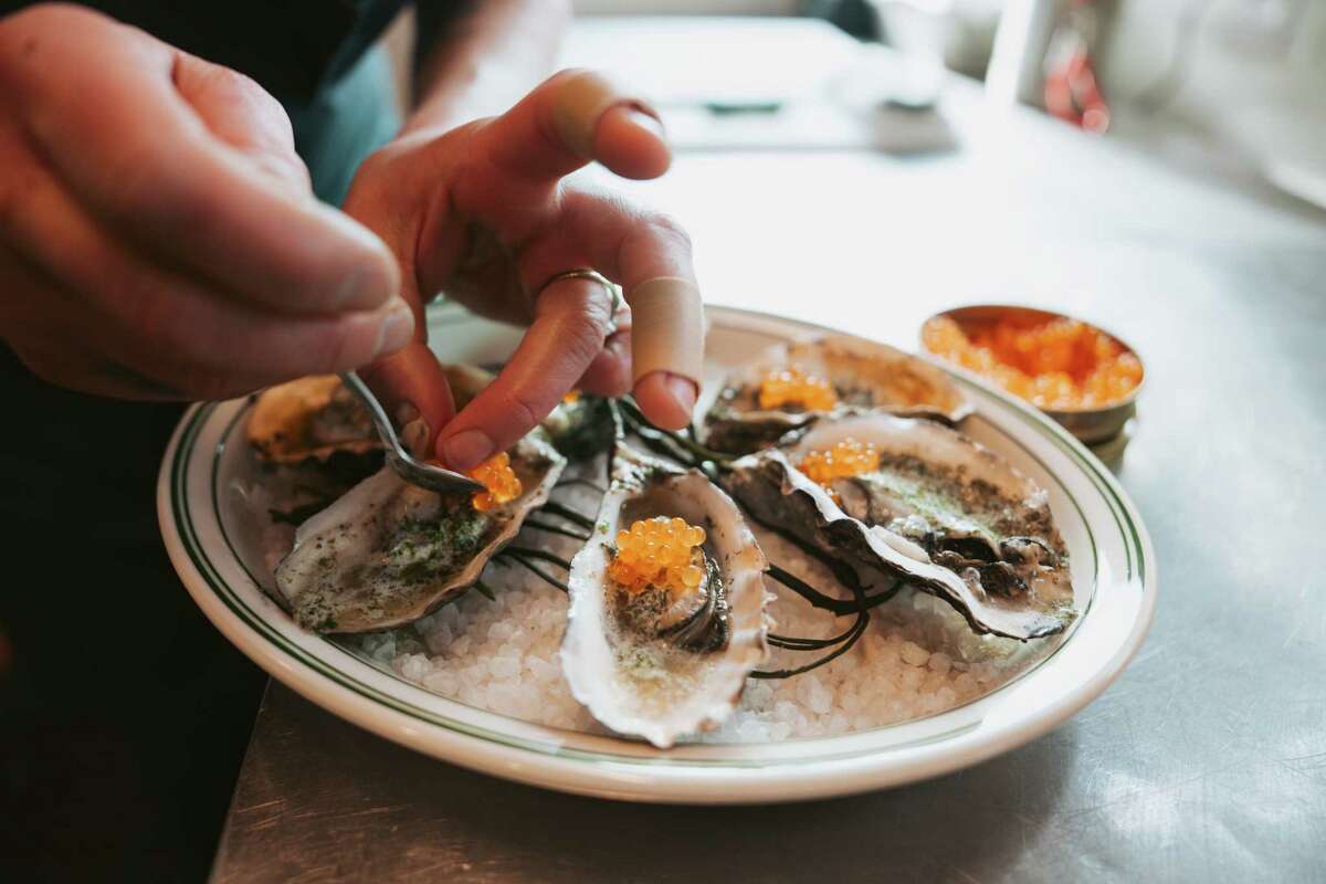 Chef Melissa Perfit spoons trout roe on top of grilled oysters in her new restaurant, Popi's Oysterette.
