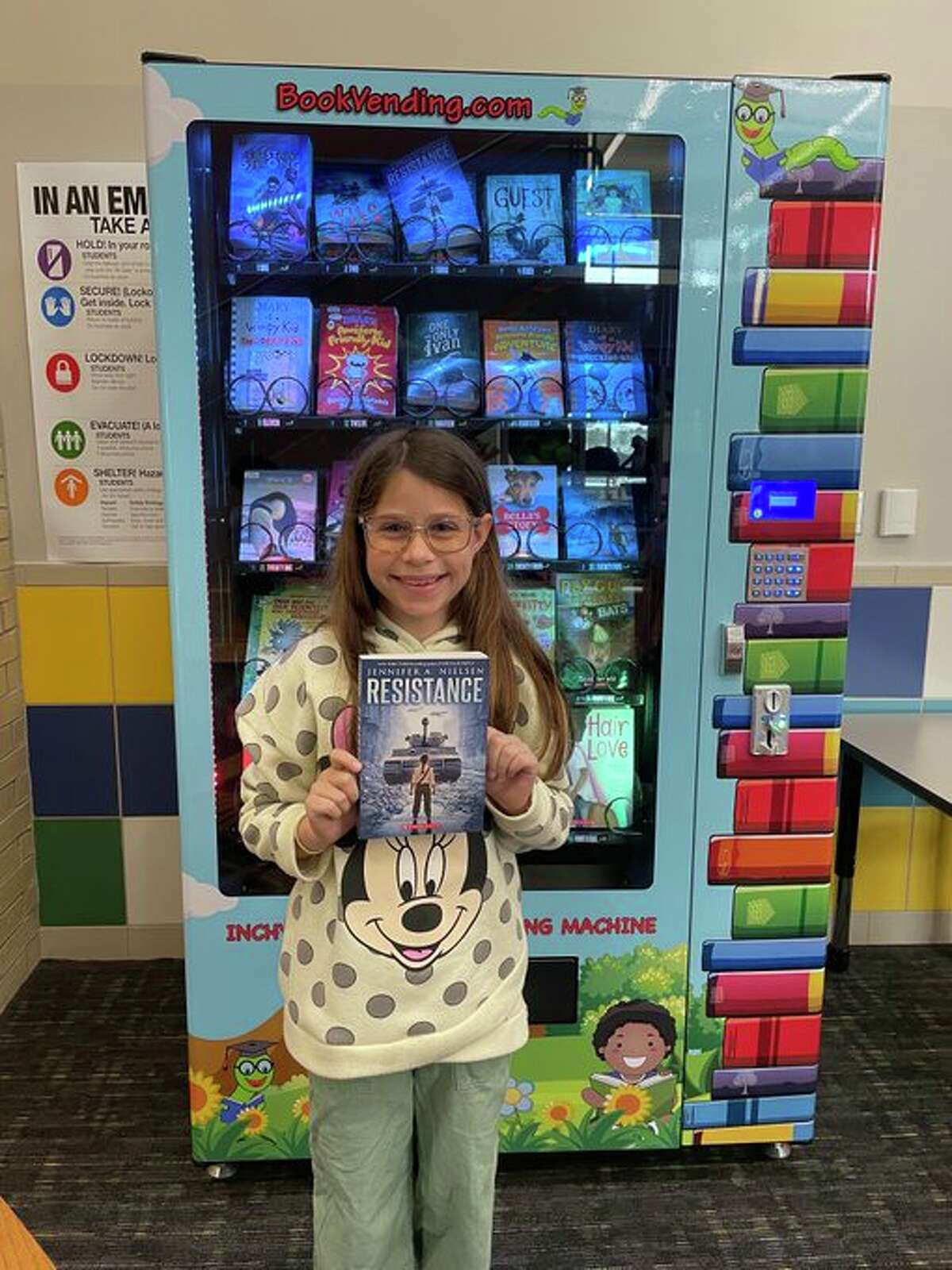 Nelson Elementary School fourth-grader Claire Knape used a token she received as a reward for taking her friend to the school nurse to get a book from the school's book-vending machine.