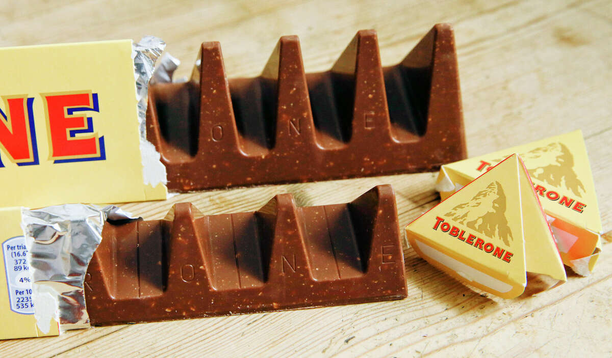 Two bars of Toblerone Swiss chocolate are shown. At front is the new-style 150 gram bar showing the reduction in triangular pieces; in the background is the older-style 360 gram bar. The makers of Toblerone are stripping images of Switzerland's famed Matterhorn and the Swiss flag from the packaging of the milk-chocolate treat to comply with "Swissness" legislation, largely because some of its production is being outsourced to Slovakia.