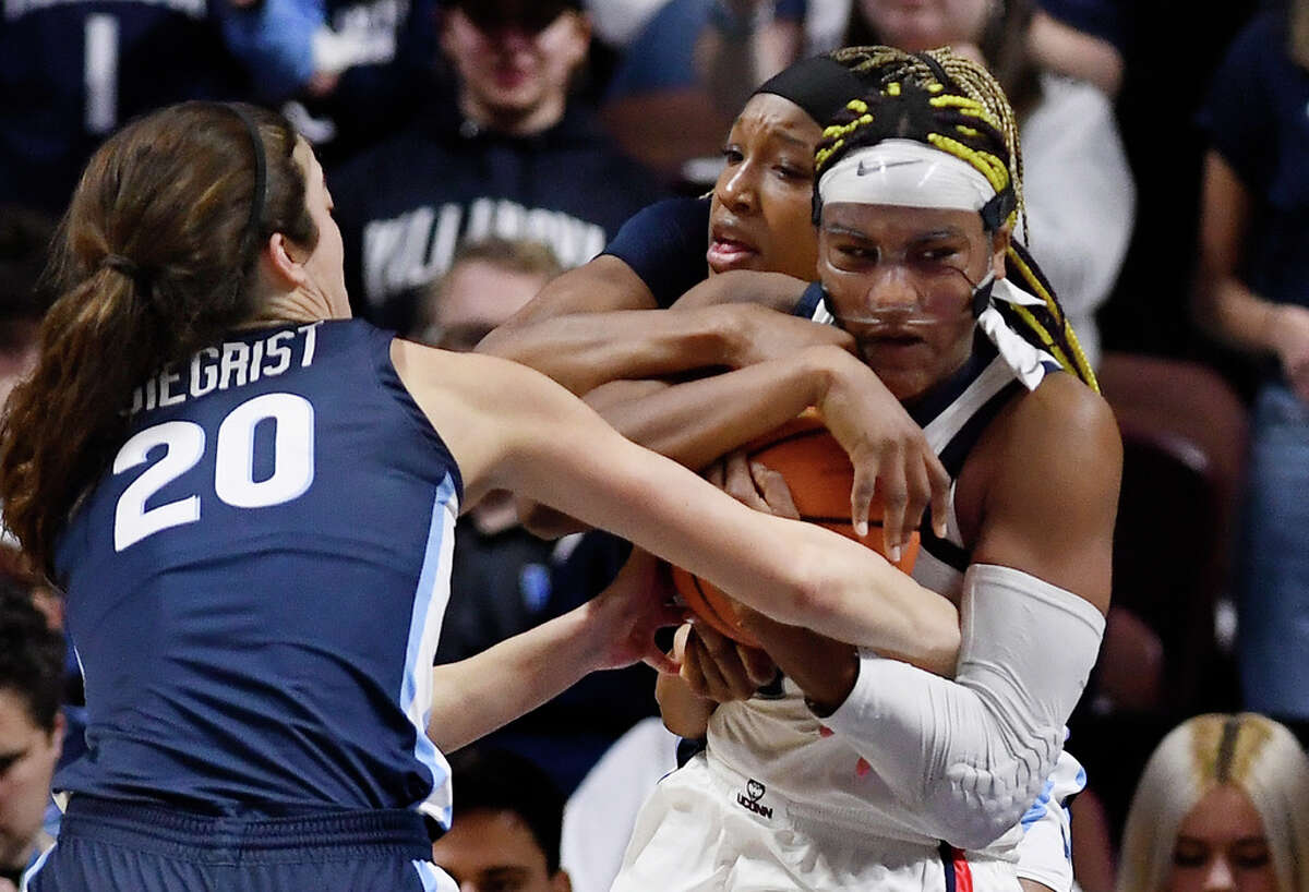 UConn's Aaliyah Edwards, right, fights for possession of the ball against Villanova's Maddy Siegrist, left, and Villanova's Christina Dalce, back center, during the first half of an NCAA college basketball game in the finals of the Big East Conference tournament, Monday, March 6, 2023, in Uncasville, Conn. (AP Photo/Jessica Hill)