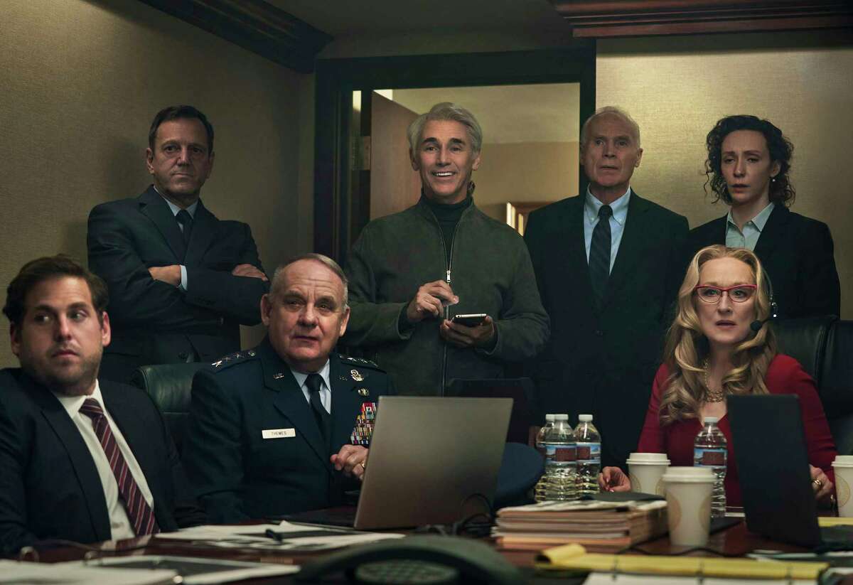 This image released by Netflix shows Mark Rylance as Peter Isherwell, standing center, with main cast members, seated from left, Jonah Hill, Paul Guilfoyle and Meryl Streep in a scene from "Don't Look Up." Rylance portrays tech billionaire Peter Isherwell. (Niko Tavernise/Netflix via AP)