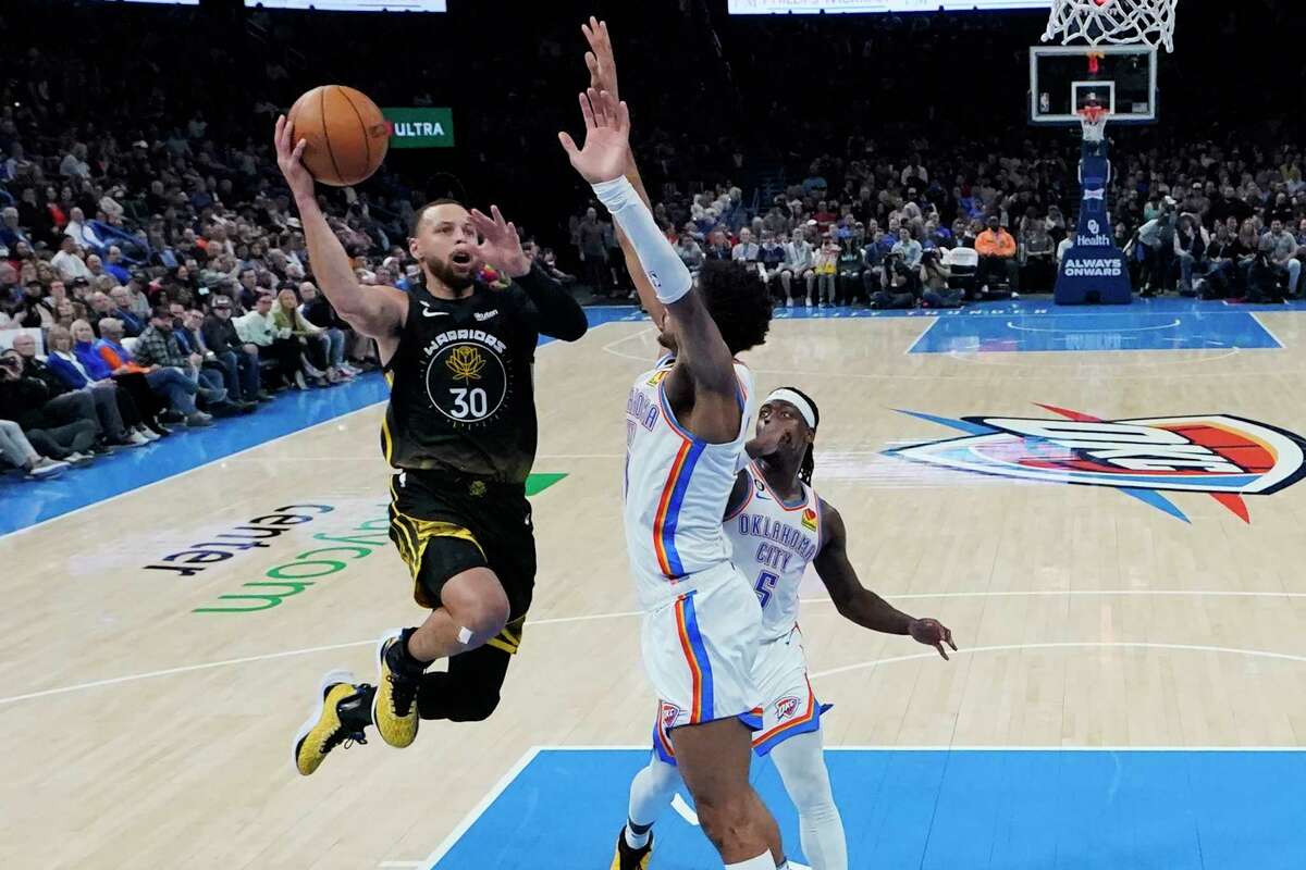 Warriors guard Stephen Curry goes to the basket in front of Oklahoma City Thunder guard Aaron Wiggins (center) and guard Luguentz Dort in the second half of Golden State's loss Tuesday in Oklahoma City.