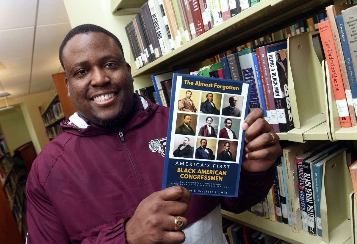 Darryl Brackeen Jr. with his book, "The Almost Forgotten: America's First Black American Congressmen," at Southern Connecticut State University's Buley Library in New Haven.