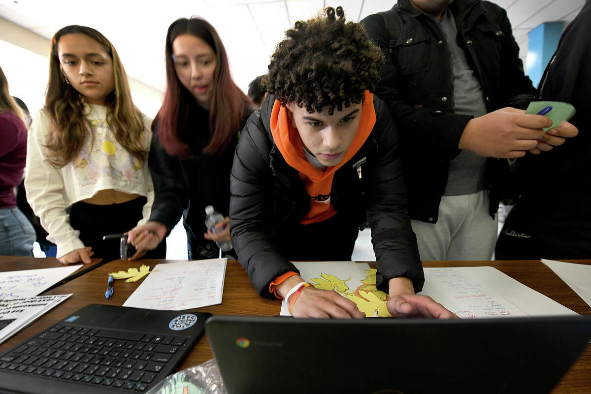 Victor Costa, 17, center, a junior, signs a petition during a "Day of Action on School Funding" at lunch time in the Danbury High School cafeteria, Wednesday, March 8, 2023.