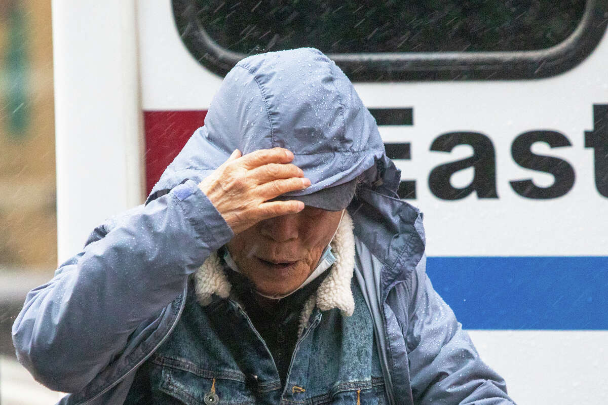 A man attempts to shield himself from raindrops during a heavy rainfall in Oakland, Calif., on March 9, 2023.