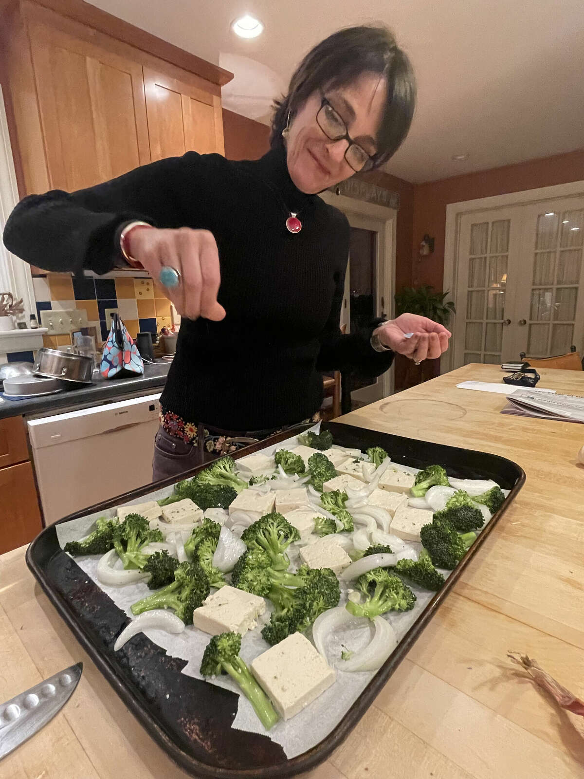 Caroline Barrett seasons pressed tofu and broccoli before roasting in the oven.