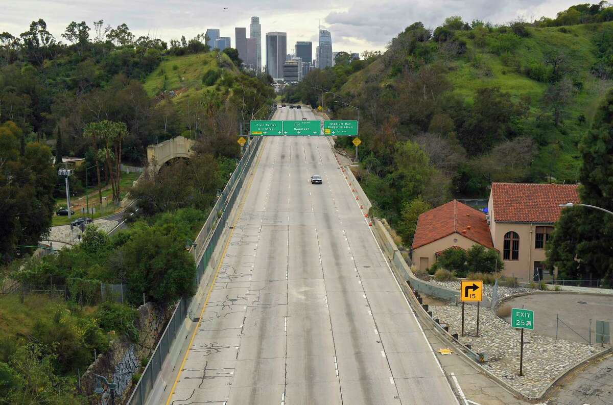 FILE - Extremely light traffic moves along the 110 Harbor Freeway toward downtown Los Angeles in the mid-afternoon of March 20, 2020.