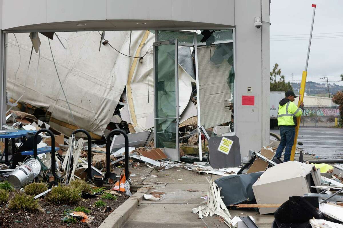 A man works next to the damage from a roof collapse at a Peet’s Coffee distribution warehouse on Friday, March 10, 2023 in Oakland, Calif. One employee was killed and another person suffered minor injuries.