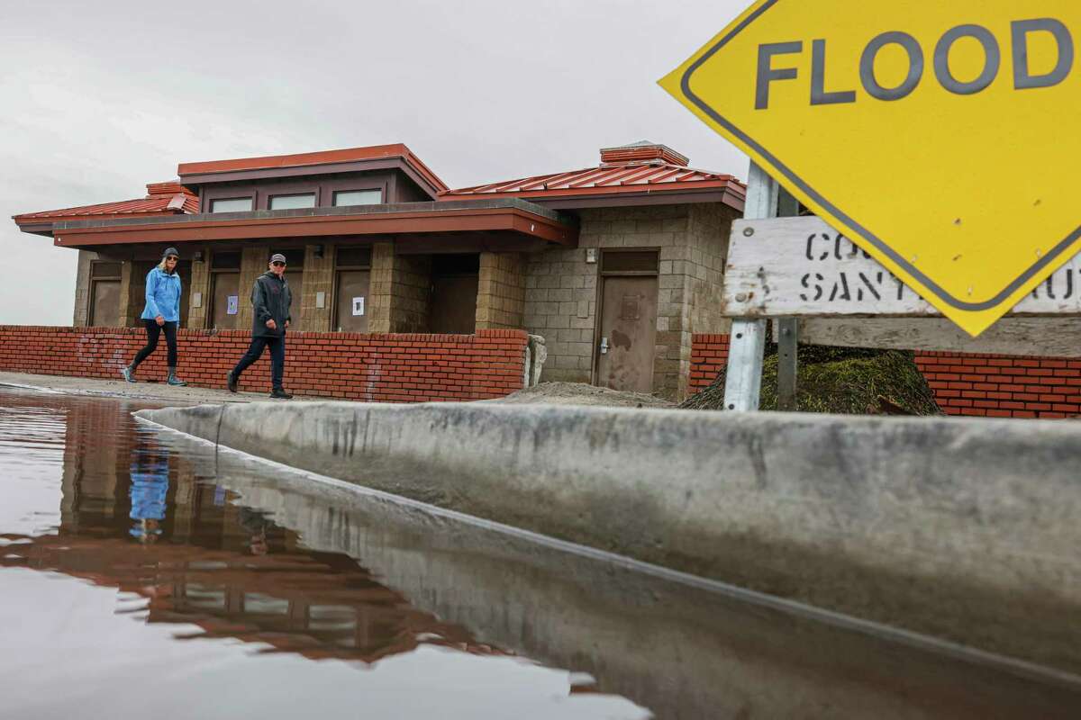 周五，人们沿着圣克鲁斯县的德尔马海滩散步。该县在该地区发布了洪水警报。