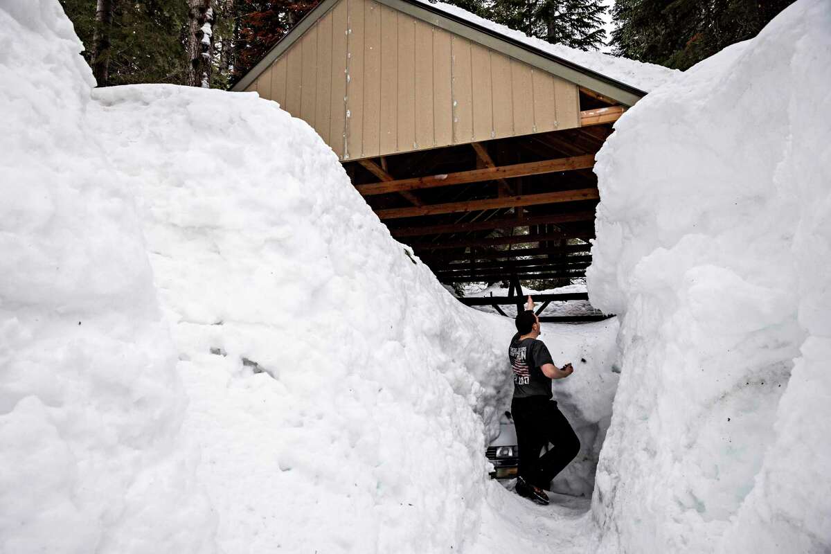 Alex Bernard is dwarfed by the snow pile outside a carport at his home in Kingvale (Nevada County).