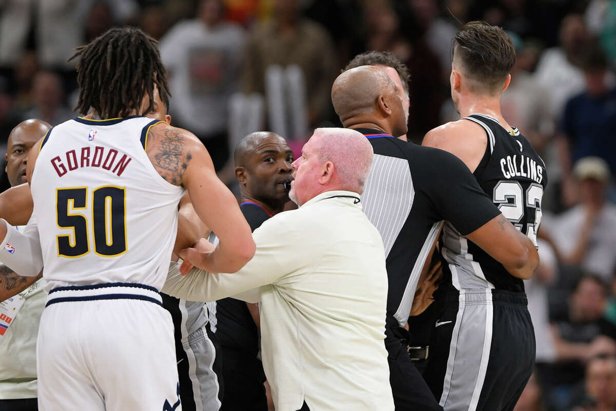 San Antonio Spurs' Zach Collins, right, is restrained after an altercation on the court in the second half of an NBA basketball game against the Denver Nuggets, Friday, March 10, 2023, in San Antonio. (AP Photo/Darren Abate)