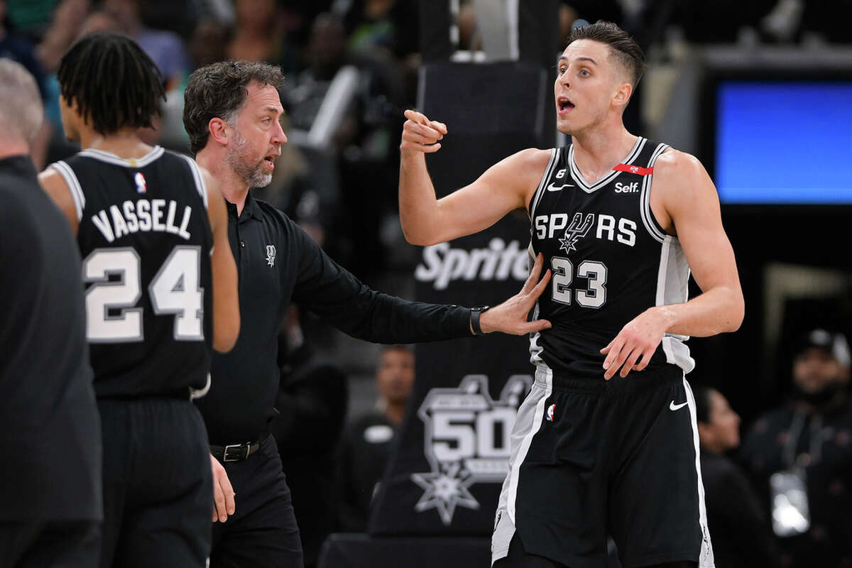 San Antonio Spurs' Zach Collins (23) is restrained by Spurs assistant coach Matt Nielsen after an altercation on the court in the second half of an NBA basketball game against the Denver Nuggets, Friday, March 10, 2023, in San Antonio. (AP Photo/Darren Abate)