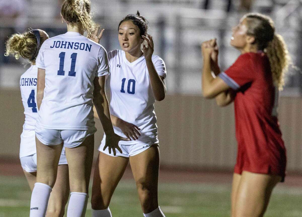 Johnson’s Camila Palacios, facing camera, celebrates her first half goal with teammates Claire Boynton, left, and Mabry Williams, second from left, Friday night, Match 10, 2023 at Comalander Stadium as a LEE player reacts during the Jaguars’ game against the Vols