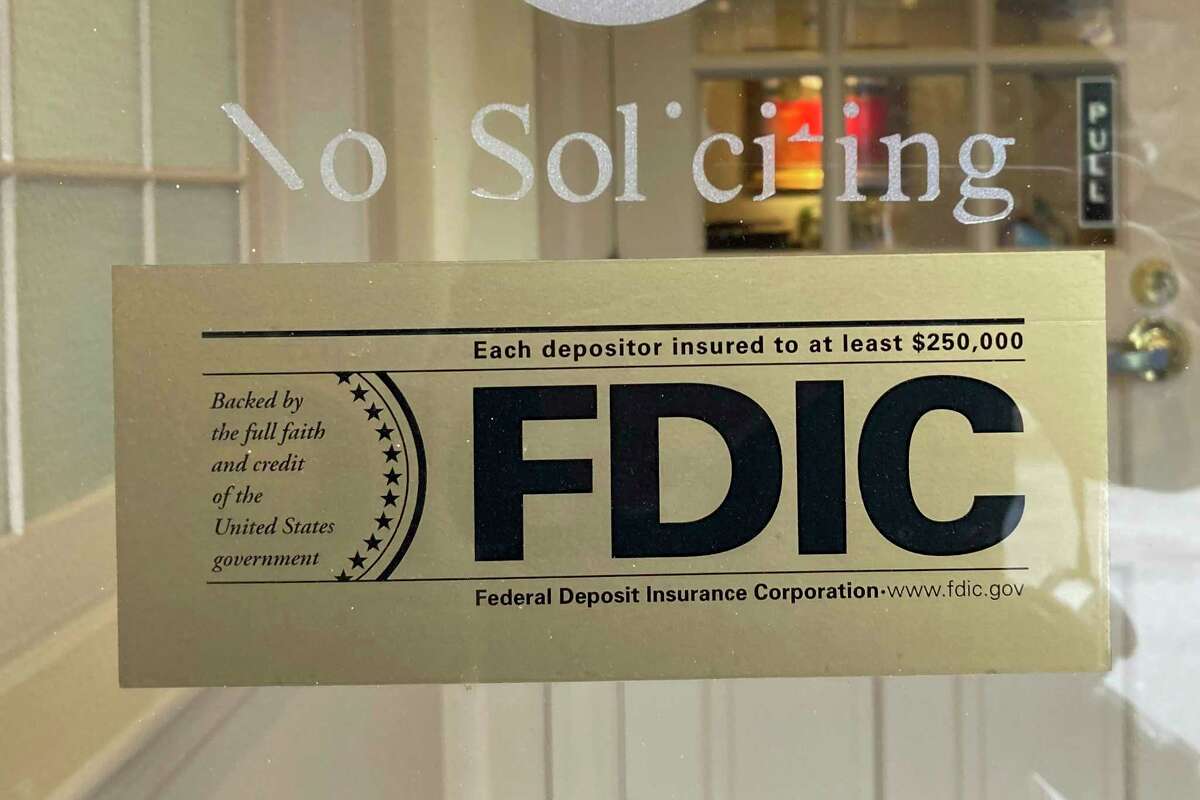 An FDIC sign is posted on a window at a Silicon Valley Bank branch in Wellesley, Mass., on Saturday, March 11, 2023. From winemakers in California to startups across the Atlantic Ocean, companies are scrambling to figure out how to manage their finances after their bank, Silicon Valley Bank, suddenly shut down on Friday. U.S. customers with less than $250,000 in the bank can count on insurance provided by the FDIC.