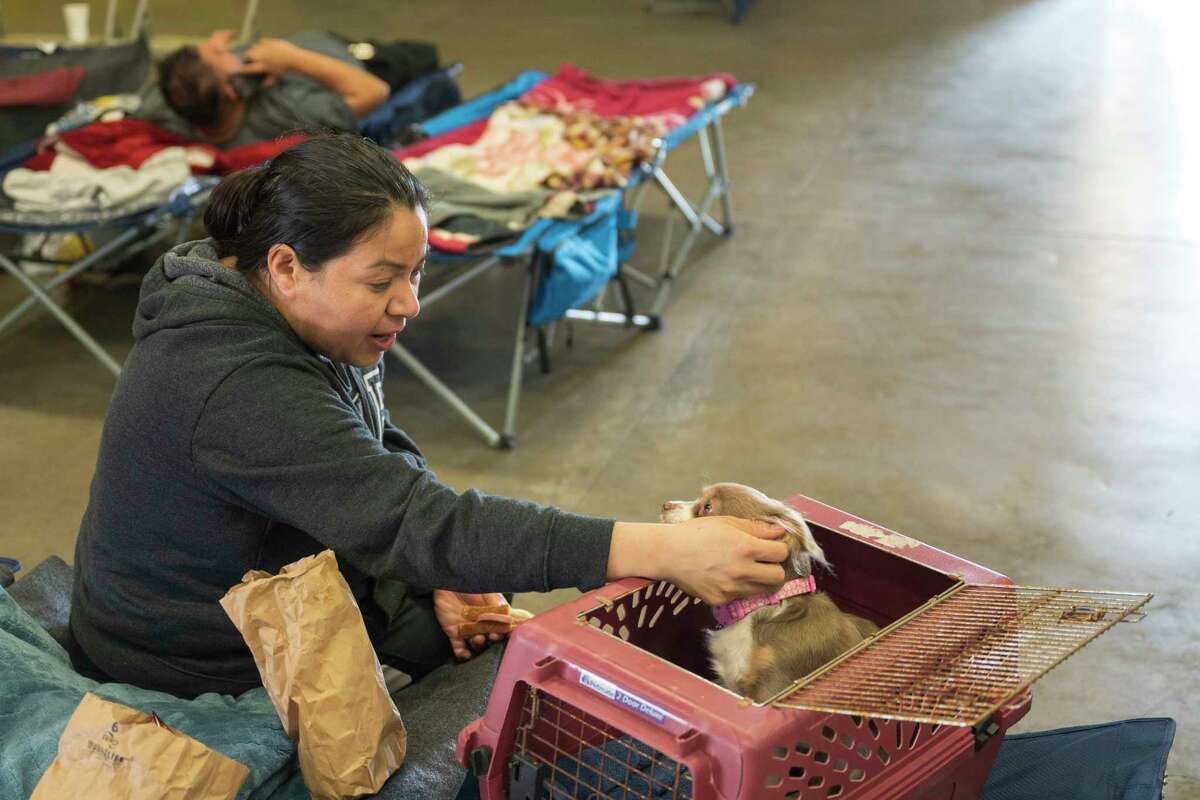 Anais Rodriguez comforts her dog, Mile, Saturday at an evacuation center at the Santa Cruz County Fairgrounds in Watsonville. They were evacuated from their Pajaro home. 