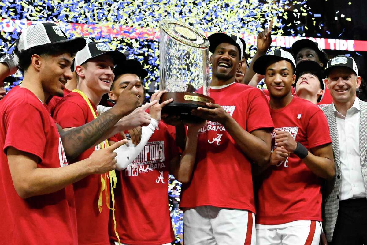 Alabama players pose with the trophy after an NCAA college basketball game against Texas A&M in the finals of the Southeastern Conference Tournament, Sunday, March 12, 2023, in Nashville, Tenn. Alabama won 82-63.