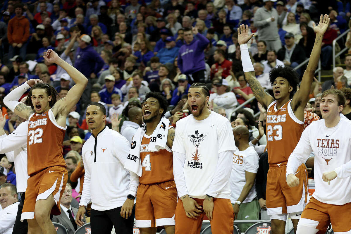 The Texas Longhorns celebrate a basket from the bench against the Kansas Jayhawks during the second half of the Big 12 Tournament Championship game at T-Mobile Center on March 11, 2023 in Kansas City, Missouri.