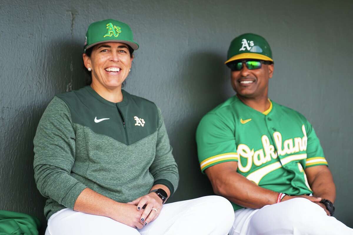 Veronica Alvarez (left), recently named the Oakland Athletics’ coordinator of player development in Latin America, sits with A’s third-base coach Eric Martins at spring training in Mesa, Ariz.