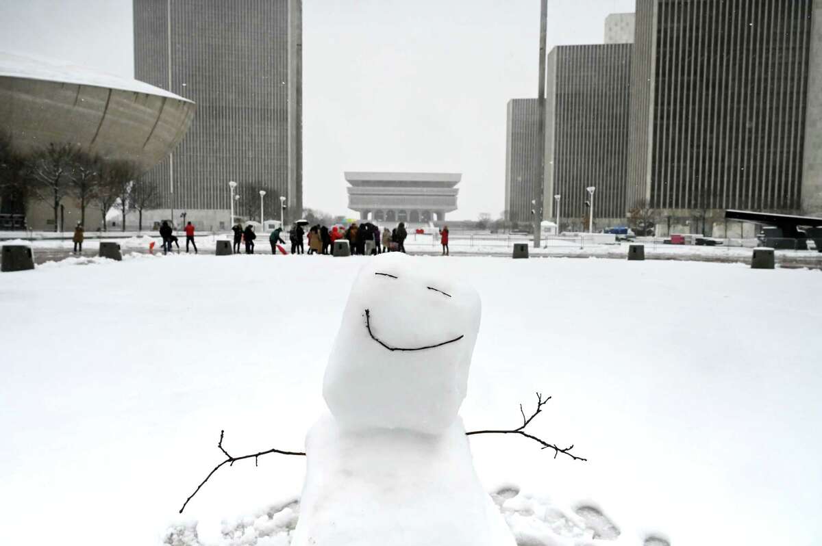 A snowman beams a happy smile from Empire State Plaza as a group of visitors stop for photos on Tuesday, March 14, 2023, in Albany N.Y.