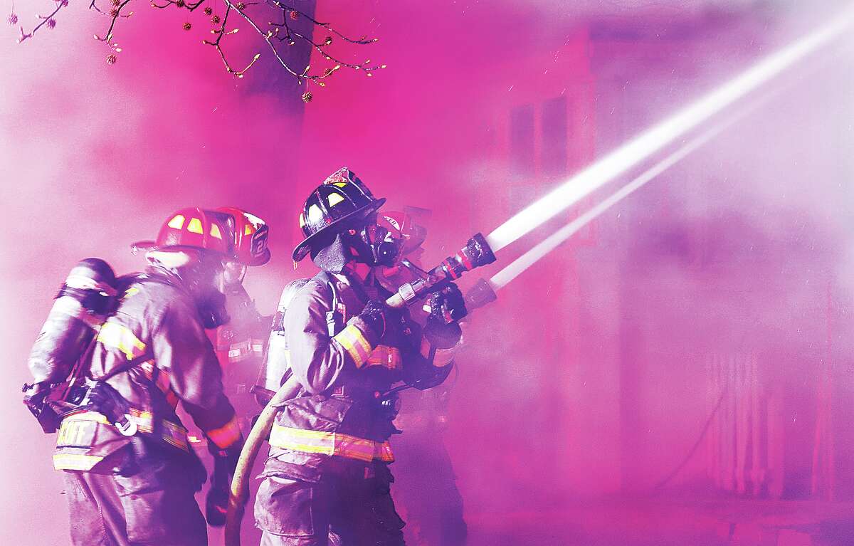 Firefighters pour water into a house early Tuesday in the 400 block of Whitelaw Avenue in Wood River under the eerie colors of dozens of strobe lights on nearby fire trucks. The house had been on the market just 14 days.