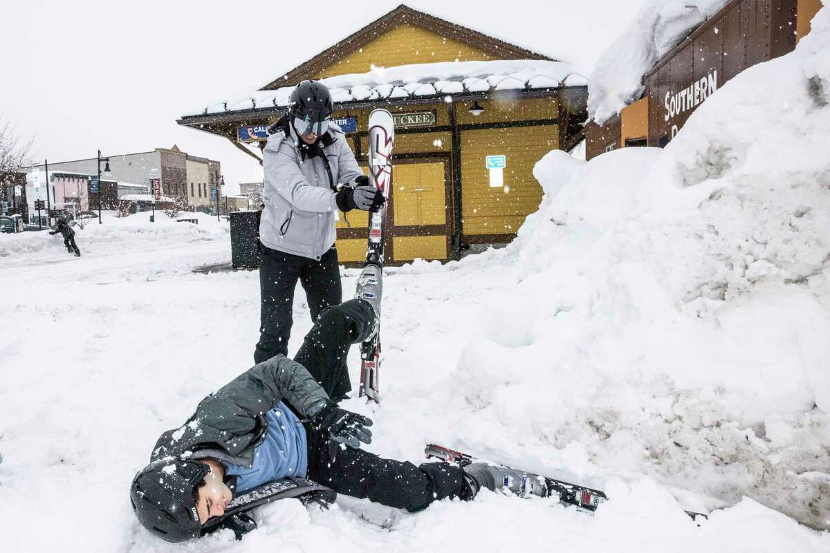 Damian Flores, top, laughs as he helps Delfino Garcia, 19, after the latter fell into the snow while trying to ski for the first time since he was 8 in Truckee. Both Flores and Garcia are visiting Truckee from Texas during spring break to ski and snowboard on March 11, 2023. 