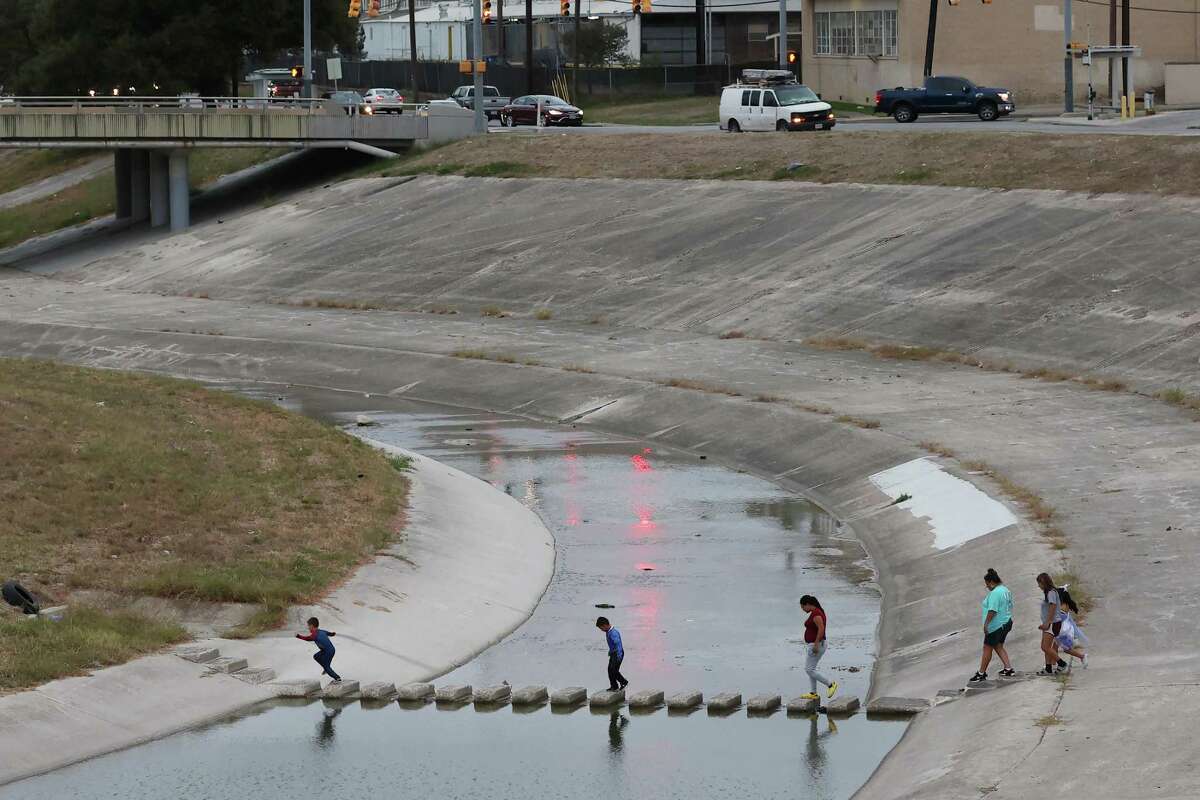 A family crosses Apache Creek by Casiano Park on Thursday, Oct. 27, 2022. The West Side waterways — including the Apache, Alazan, Martinez and San Pedro Creeks — are undergoing restorations.