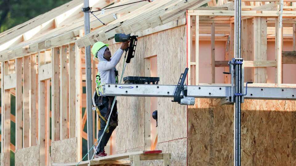 A man uses a nail done alongs the side of a home as construction continues at Woodmill Creek, a community of 189 build-to-rent, multifamily homes, Wednesday, March 15, 2023, in The Woodlands.