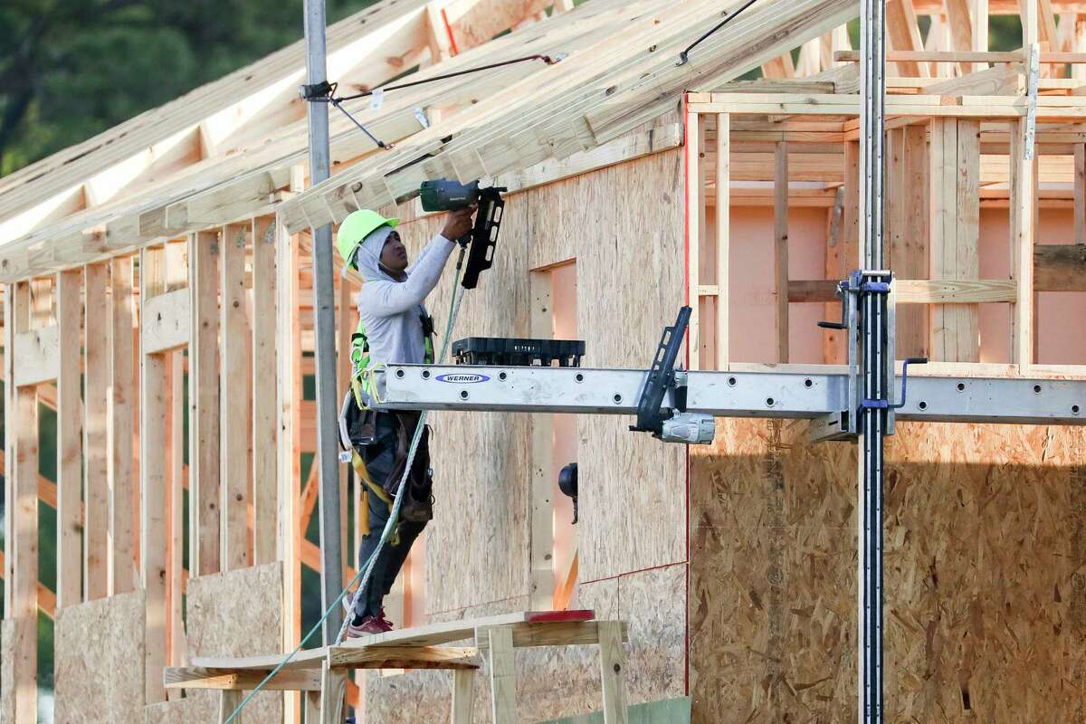 A man uses a nail done alongs the side of a home as construction continues at Woodmill Creek, a community of 189 build-to-rent, multifamily homes, Wednesday, March 15, 2023, in The Woodlands.