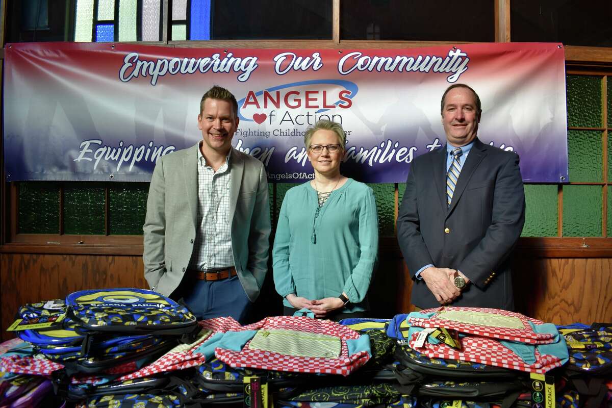 Horizon Bank representatives Chad Nastoff (left) and Tom Rowland (right) stand with Angels of Action Director Kim Easler with the backpacks donated to the Big Rapids nonprofit in support of local children and families.