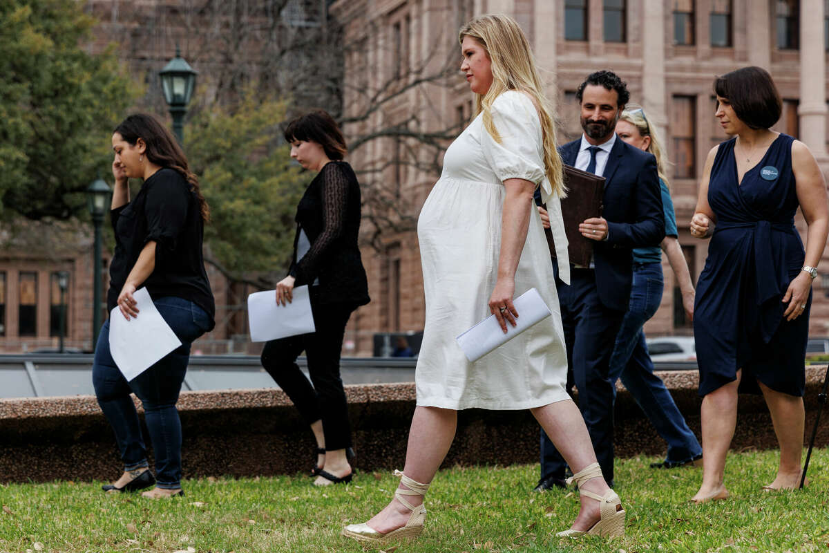 Lauren Miller, center, and other plaintiffs of the The Center for Reproductive Rightsâ landmark abortion lawsuit, walk to the podium to share their stories during a press conference held outside of the State Capitol in Austin, Texas, Tuesday, March 7, 2023. Miller was pregnant with twins when she found out at 12-weeks that one would likely not survive due to a severe genetic condition called Trisomy 18. She traveled to Colorado to have a procedure called selective fetal reduction to abort the baby and her other baby is expected to be born in the coming weeks.