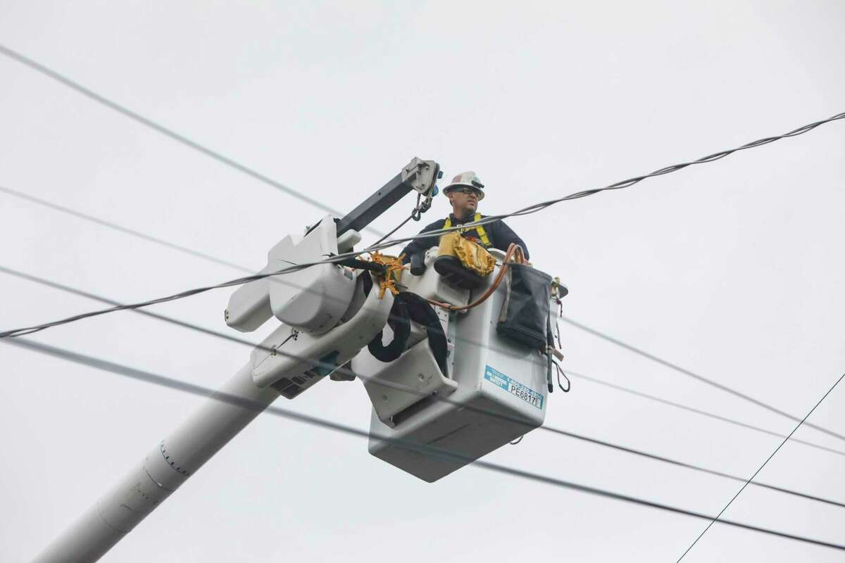 PG&E workers work on power lines. A day after a powerful storm blew through the Bay Area, around 155,000 PG&E customers were still without power. 